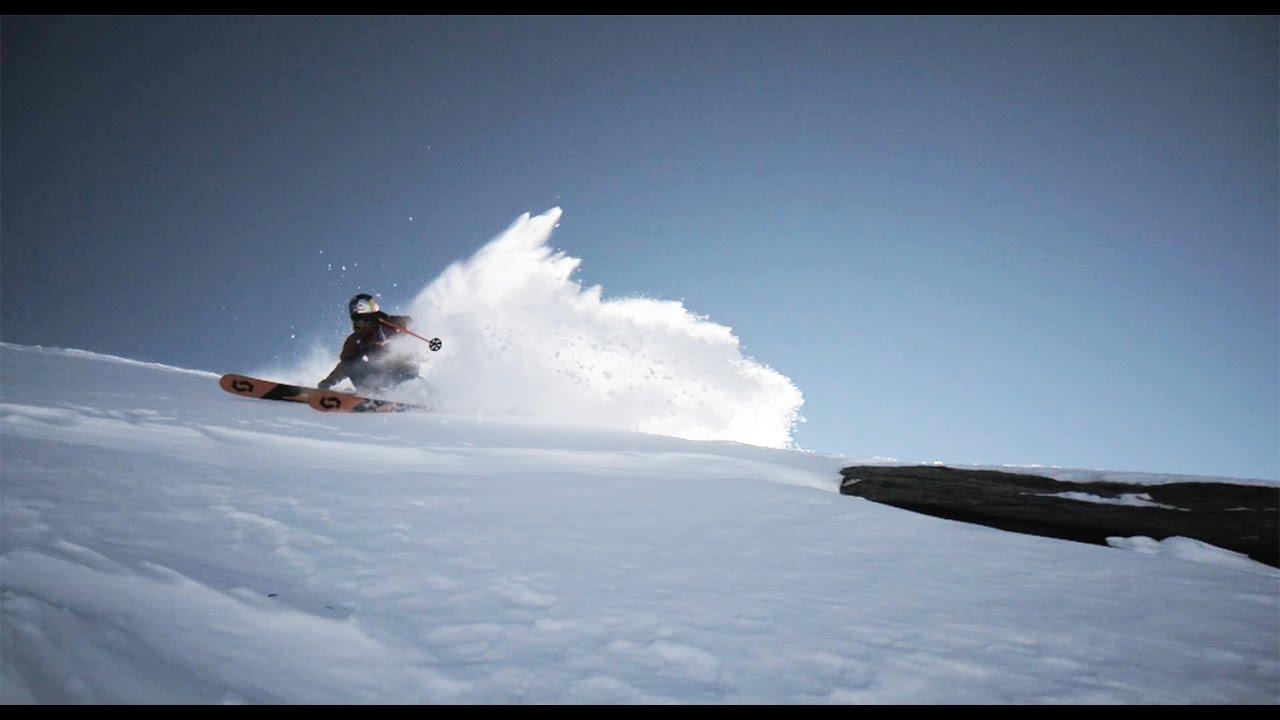 Un esquiador levanta una cortina de nieve a contraluz bajo un cielo azul