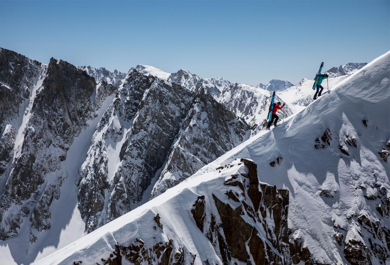 Dos esquiadores avanzan por un filo de nieve sobre los couloirs