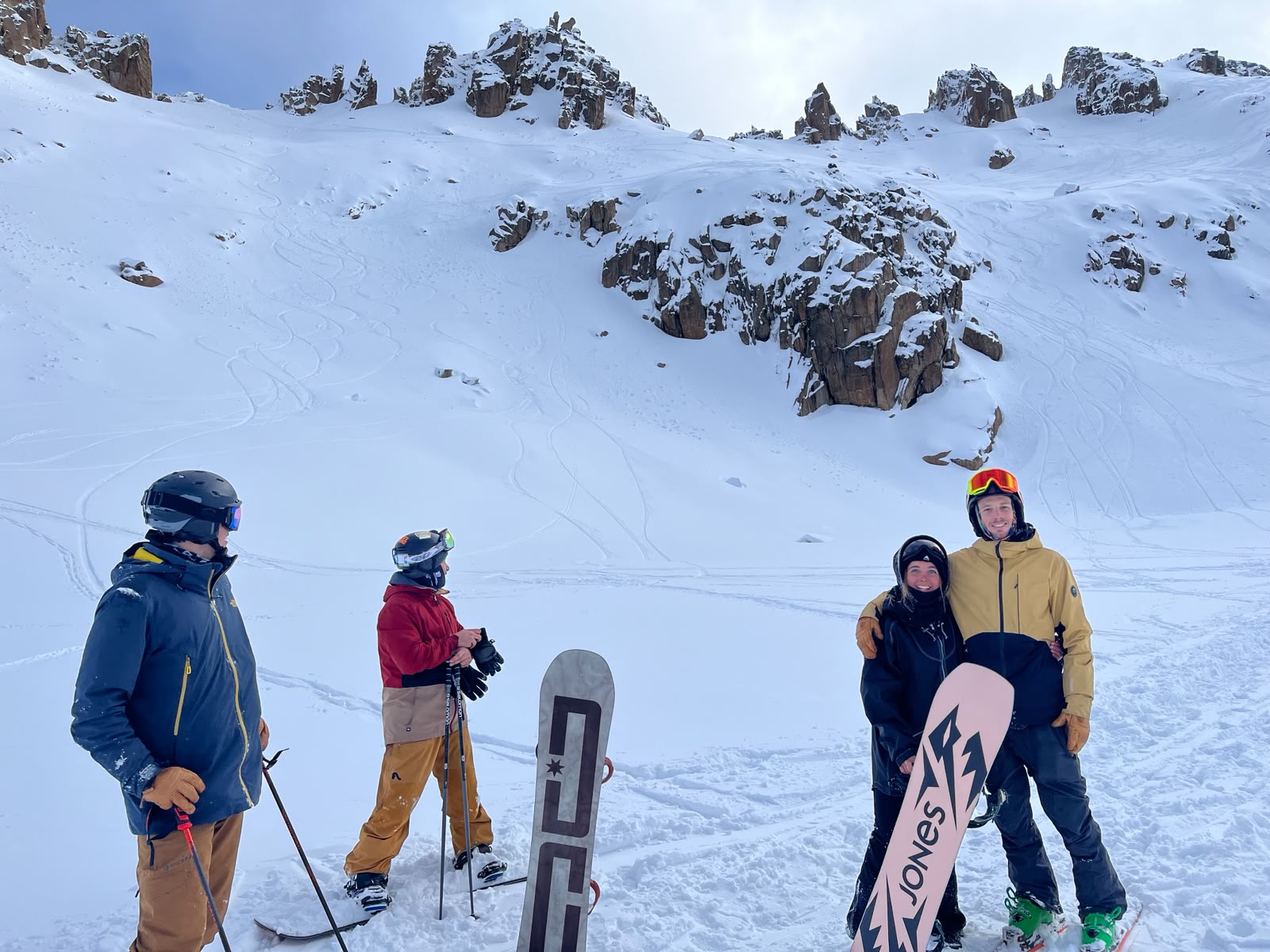 Un grupo de amigos con tablas y esquís en la ladera, bajo el sol