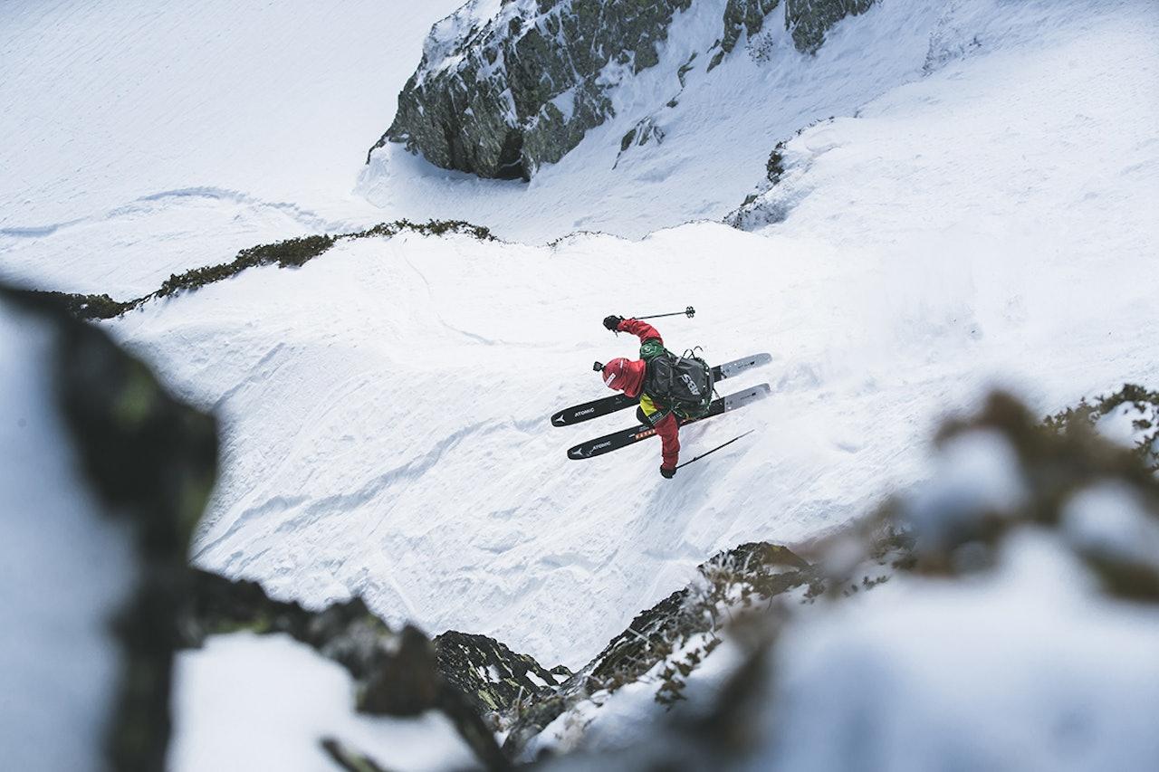 Esquiador saltando desde una roca hacia la nieve profunda