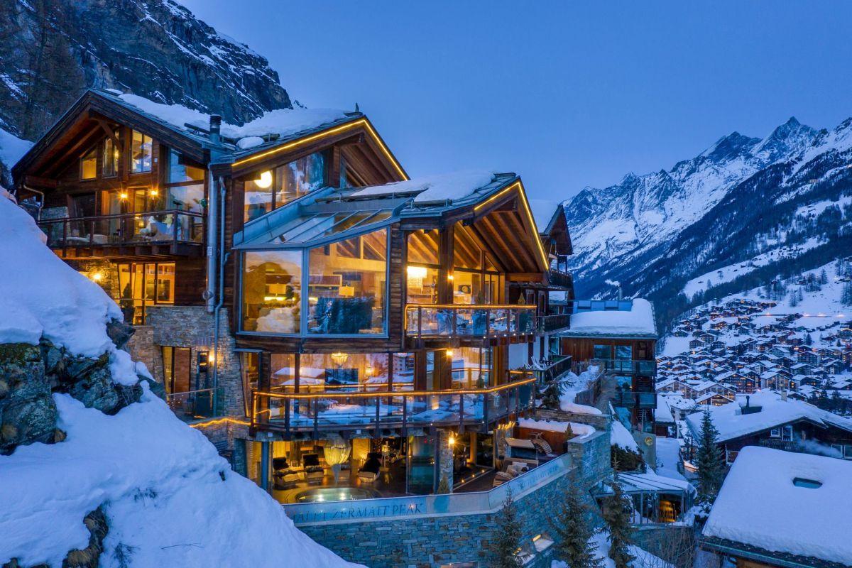 Un lodge de lujo iluminado al anochecer sobre el pueblo nevado