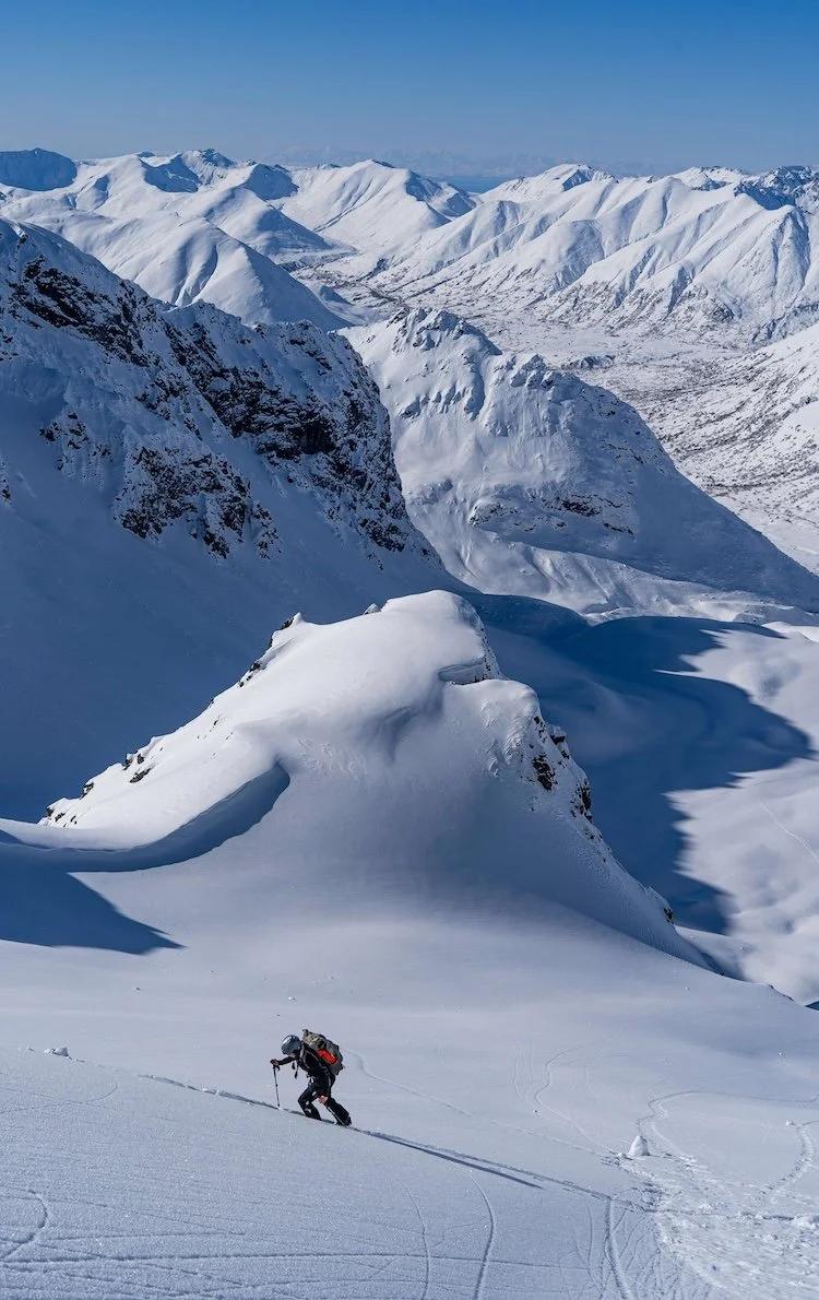 Esquiador de travesía ascendiendo una loma de nieve